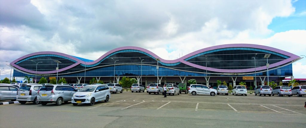 Parking area of Domine Eduard Osok Airport Sorong with unique airport building in the background