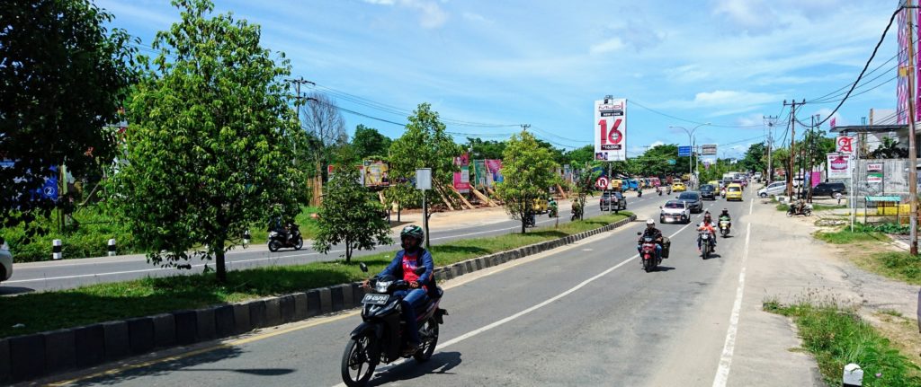 Main road in Sorong with cars, motorbikes, and angkots