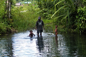 Papuan man with two kids in a river in West Papua